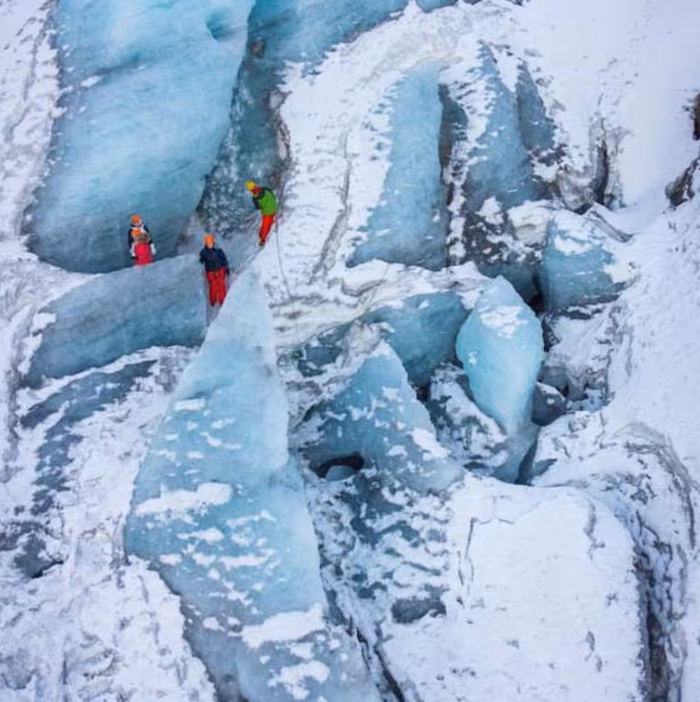 Climbers with helmets and ropes scaling blue ice wall on Solheimajokull glacier