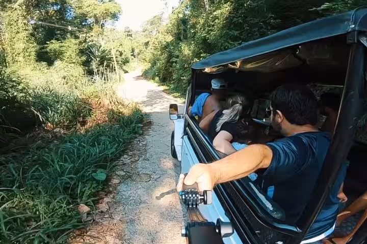 Adventurers on a private jeep tour explore lush Paraty trails, capturing scenic views and vibrant nature.