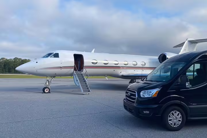 Private jet with open stairs on tarmac next to black transfer van at VSA airport