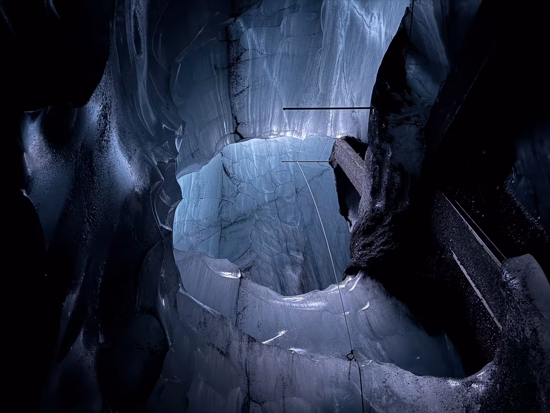 Roped descent into Katla ice cave on a private tour, showcasing layered blue ice walls and volcanic ash streaks