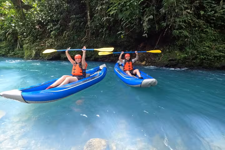 Two kayakers enjoy a private adventure on the vibrant blue waters of Río Celeste, surrounded by lush tropical greenery.