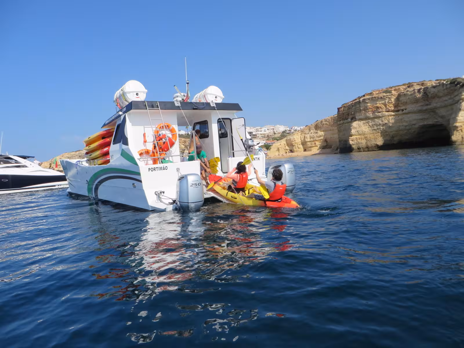 Guests starting a private kayak tour from support boat near Portimão, exploring Algarve cliffs, sea caves and golden beaches