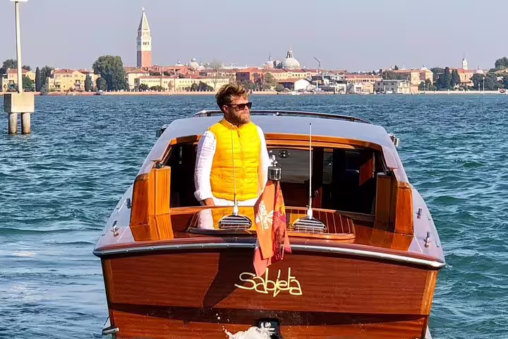 Man enjoying a Private LimoBoat tour with Venice's stunning skyline, perfect for exploring Murano, Burano, and Torcello.
