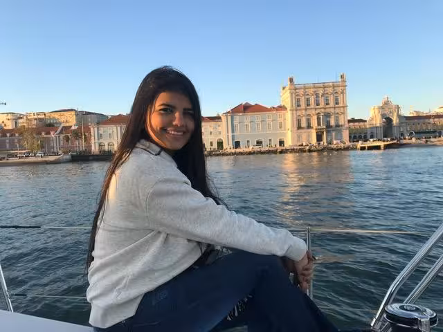 Traveler relaxing on a private Lisbon sightseeing cruise with waterfront skyline views along the Tagus River at sunset