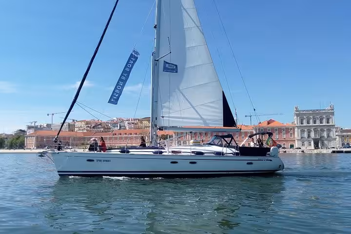 Sailing yacht gliding on the Tagus River during a private Lisbon sailing cruise with waterfront and blue sky