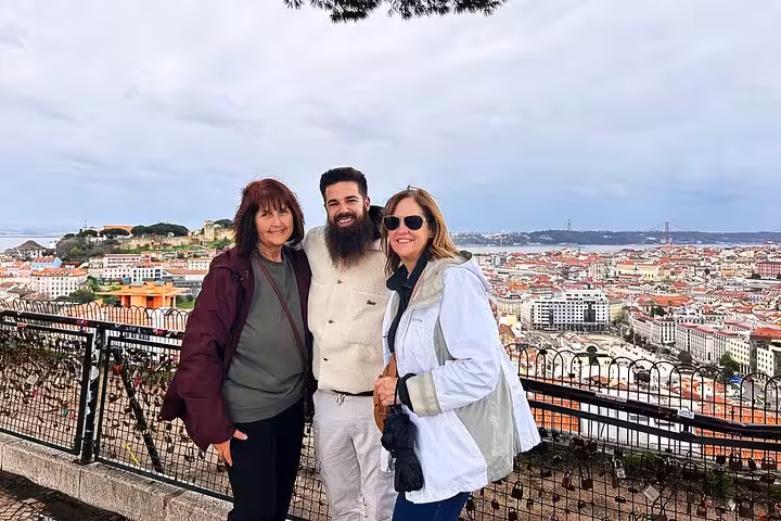 Private Lisbon tuk tuk tour photo stop at a viewpoint, with guide and guests over sweeping city panoramas
