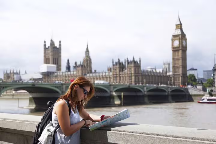 Tourist exploring London with a map by Big Ben and the Houses of Parliament during a private kickstart city tour.