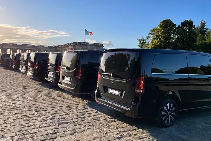 Fleet of black Mercedes luxury vans lined up on cobblestones outside Palace of Versailles, France