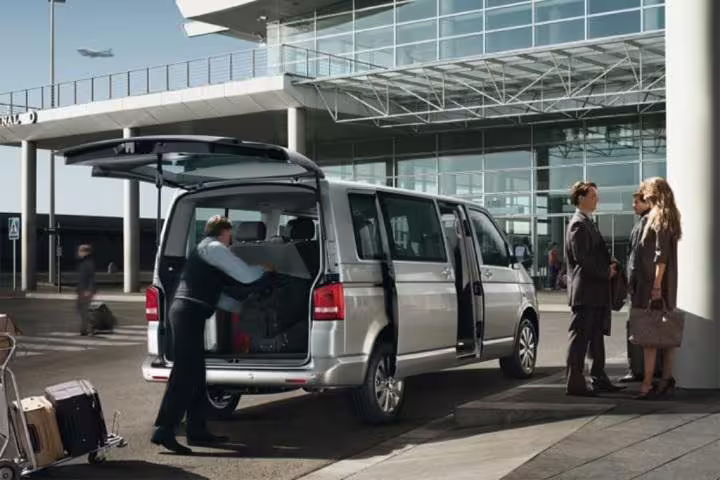 Private minivan transfer service from Naples airport to Praiano with driver loading luggage for arriving passengers