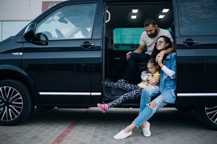 Family relaxing by a private minivan, Venice to Canazei or Ortisei transfer with door-to-door service