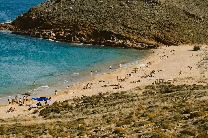 Secluded Mykonos sandy beach bay with turquoise water and sunbathers, visited on a Private Mykonos Classic Island Tour