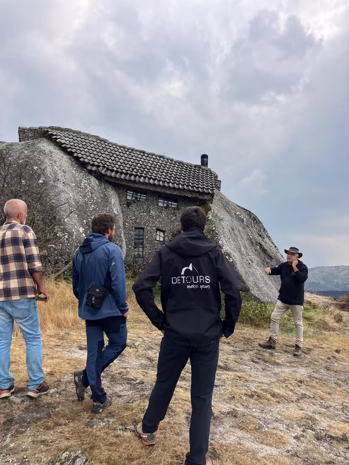 Tour group exploring unique stone house built into rock, showcasing cultural aspect of private nature tour.
