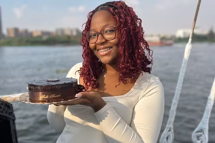 Guest holding birthday cake on a private Nile boat cruise in Cairo, ideal for lunch or dinner celebration