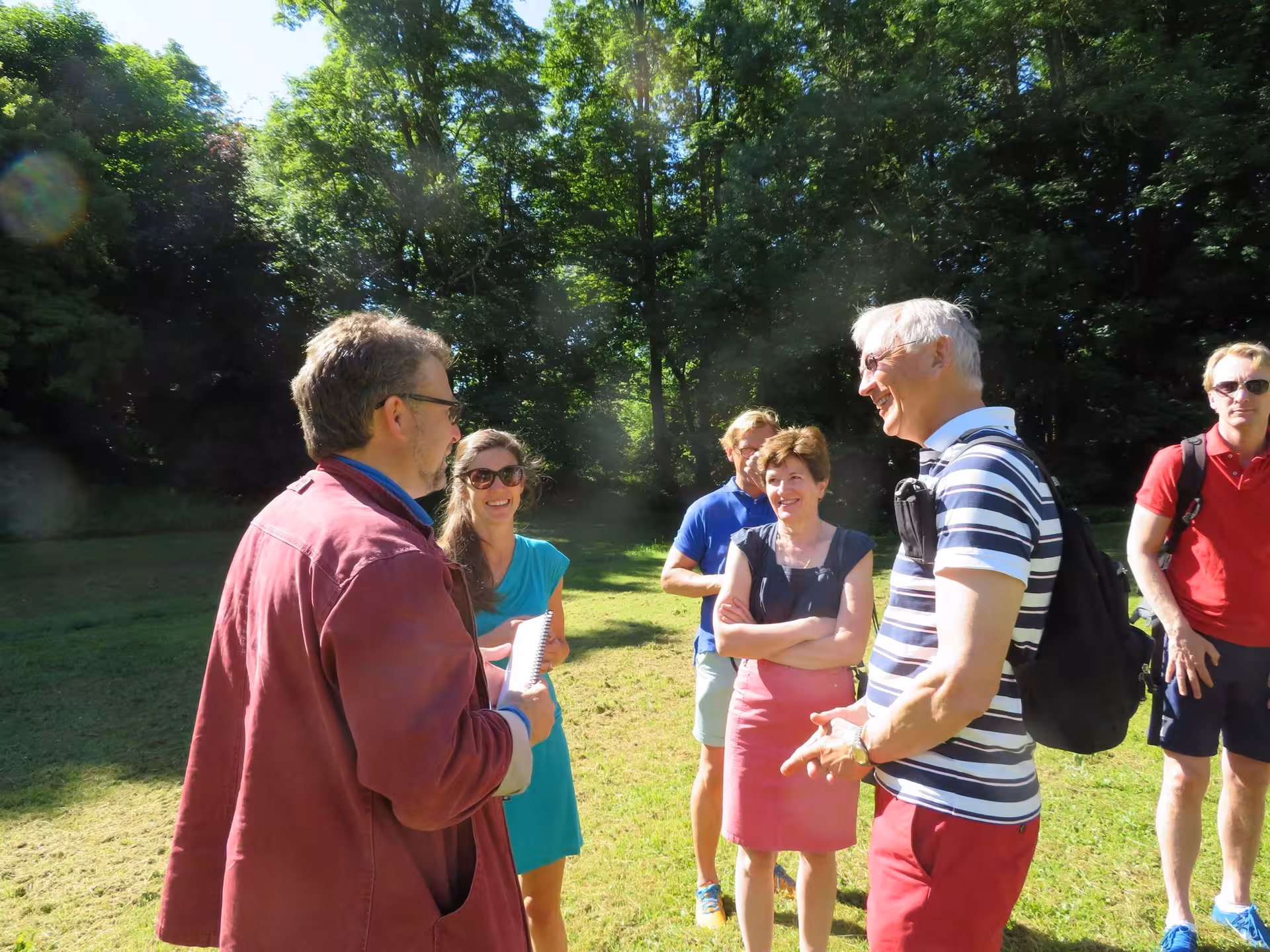 Tour guide speaking with small group of tourists outdoors in sunny Normandy countryside