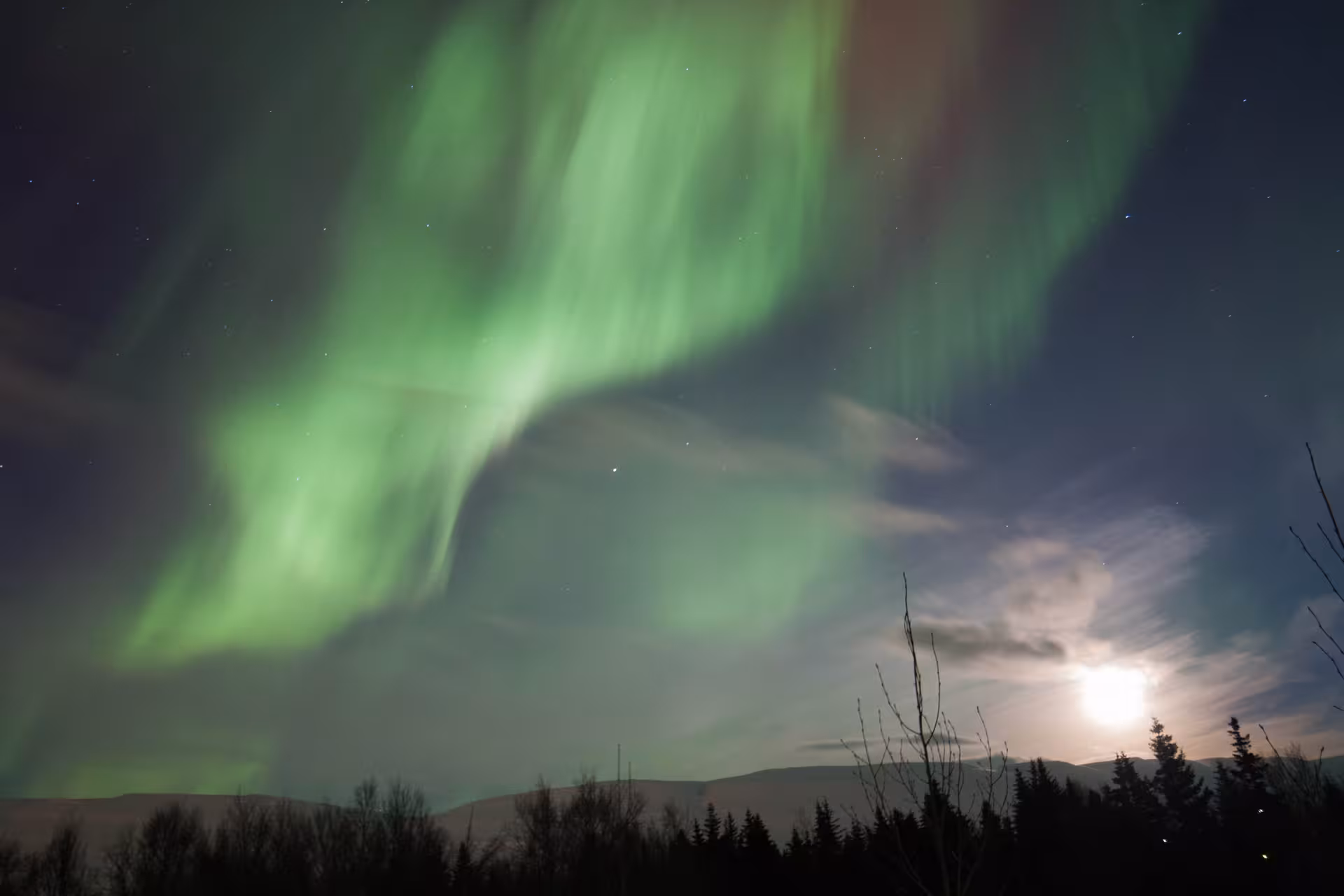 Vibrant Northern Lights painting the night sky above moonlit landscape, ideal for private tours.