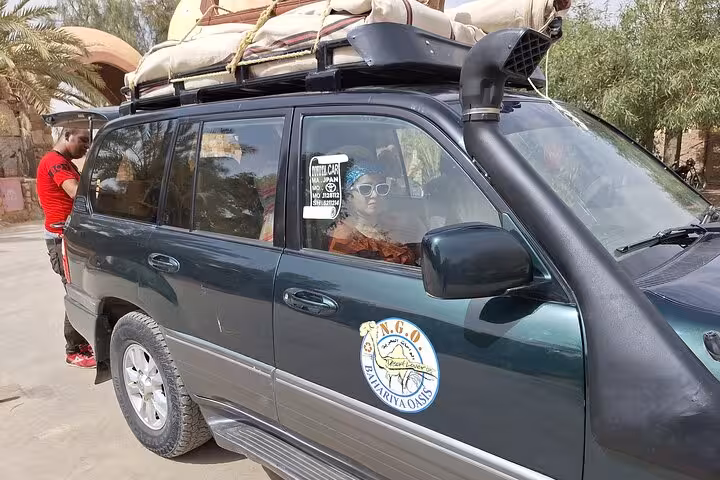 Tourists prepare for an adventurous journey in a 4x4 vehicle for an all-inclusive private overnight camping in the White and Black Desert.