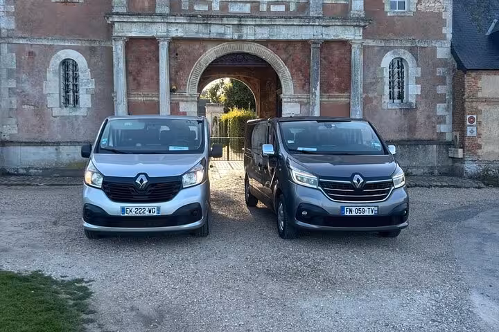 Two Renault Trafic vans parked in front of a historic French château gateway