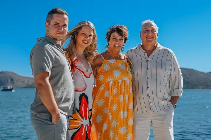Smiling group enjoying a private photoshoot by the sea in Elounda, capturing vacation memories on a sunny day.