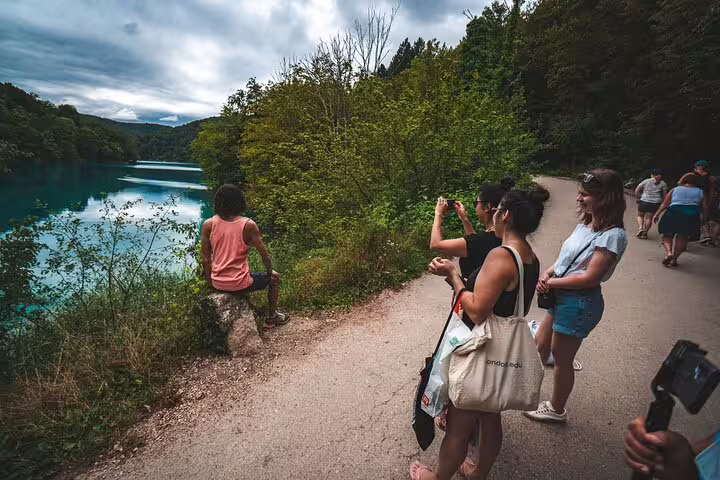 Guests on a private Plitvice Lakes tour walking the lakeside trail beside turquoise water in Croatia