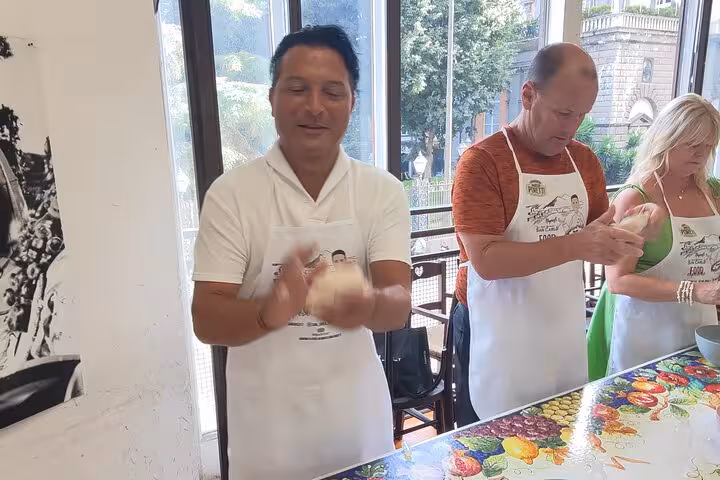 Participants in a private Rome cooking class joyfully kneading dough, highlighting a hands-on Italian culinary experience.