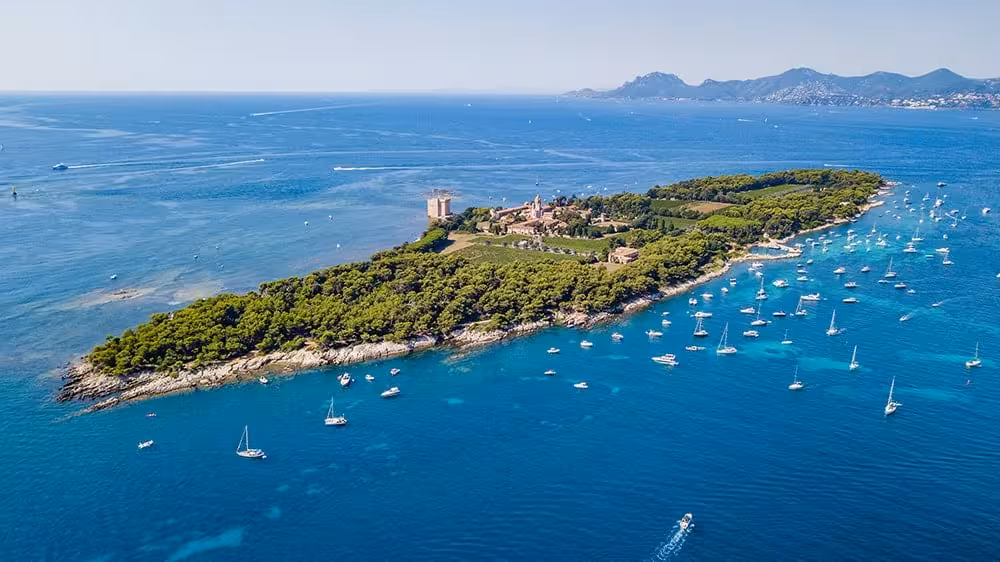 Aerial view of Île Saint-Honorat with sailboats anchored in turquoise waters, French Riviera