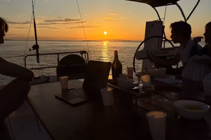 Sunset view from a private sailing boat deck in Portofino with guests, drinks, and glowing horizon over the Ligurian Sea