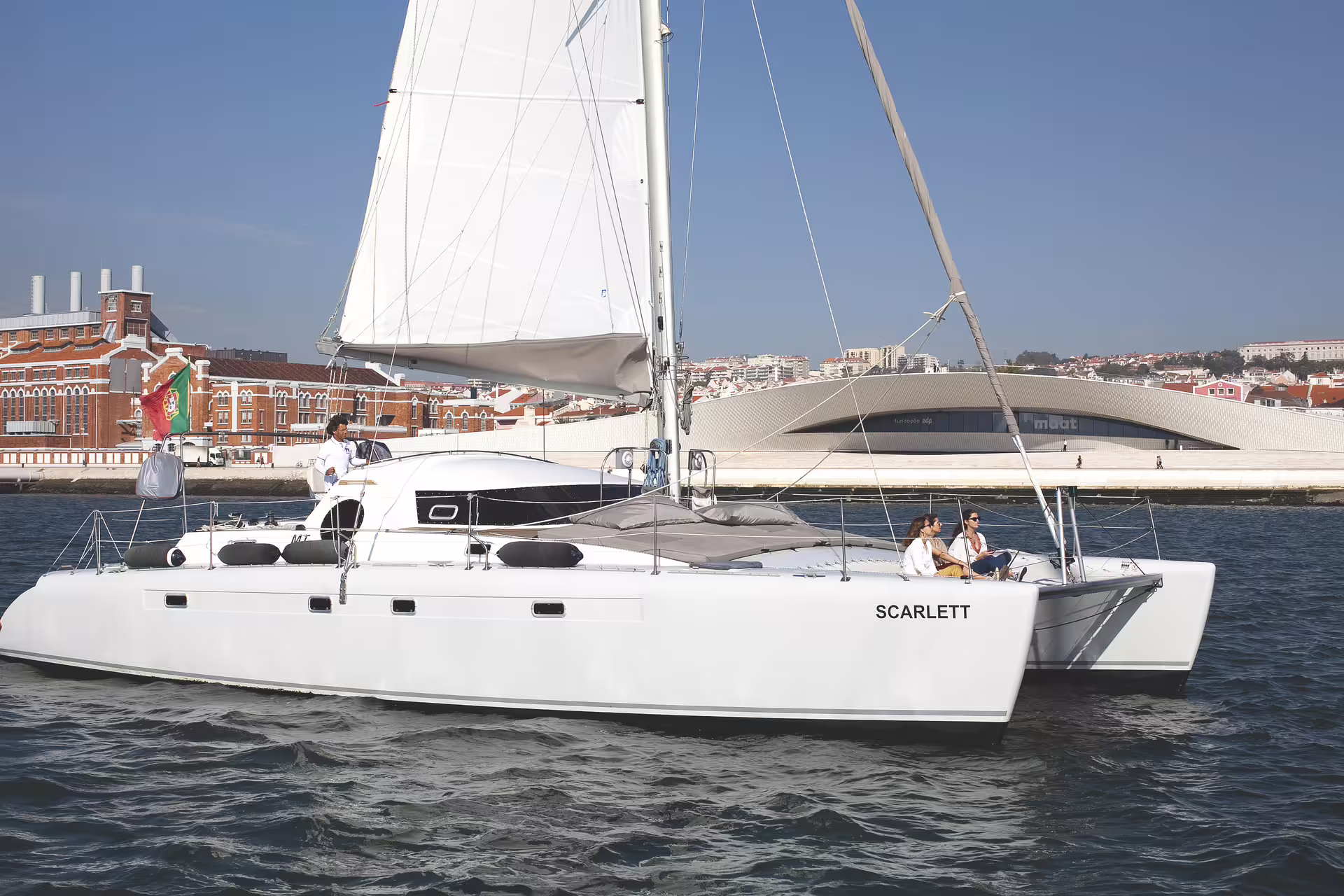 Sail past Lisbon's iconic waterfront on the luxurious catamaran 'Scarlett' during a private boat tour.