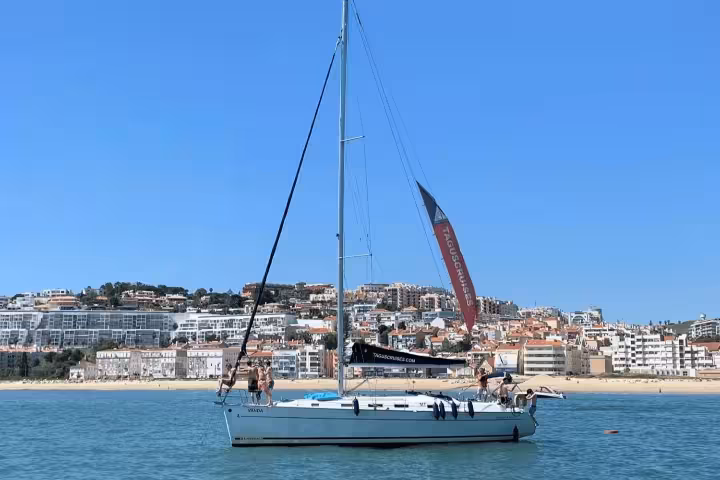 Sailboat on Oeiras beach with 'Clean & Safe' seal, ideal for a private 4-hour sailing trip in sunny Portugal.