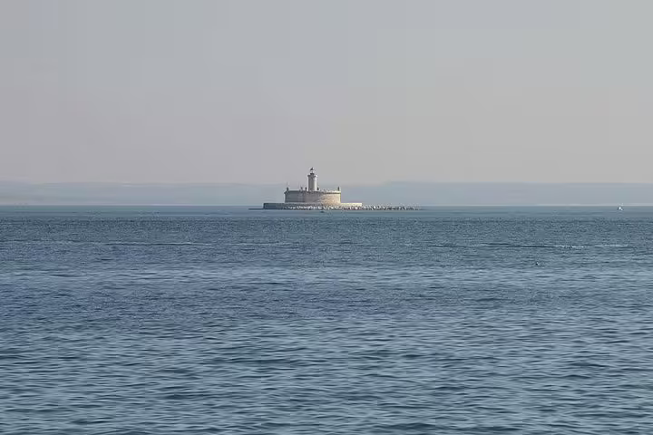 Scenic view of a distant lighthouse on a calm sea during a private sailing trip near Oeiras beach.