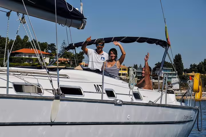 Group enjoying a private sailing trip on a yacht near Oeiras beach under sunny skies.