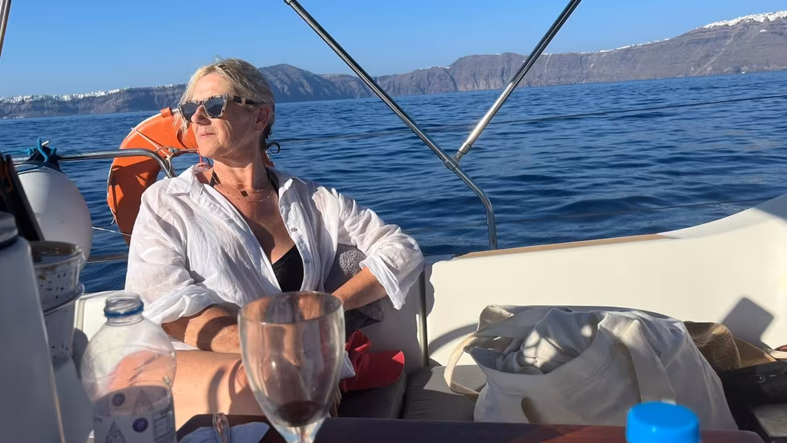 Guest relaxing on private Santorini sailing day tour with caldera cliffs and Aegean Sea views