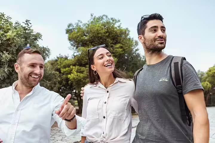 Three tourists enjoying a private full-day sightseeing tour in Santorini, exploring with a local guide under a clear sky.
