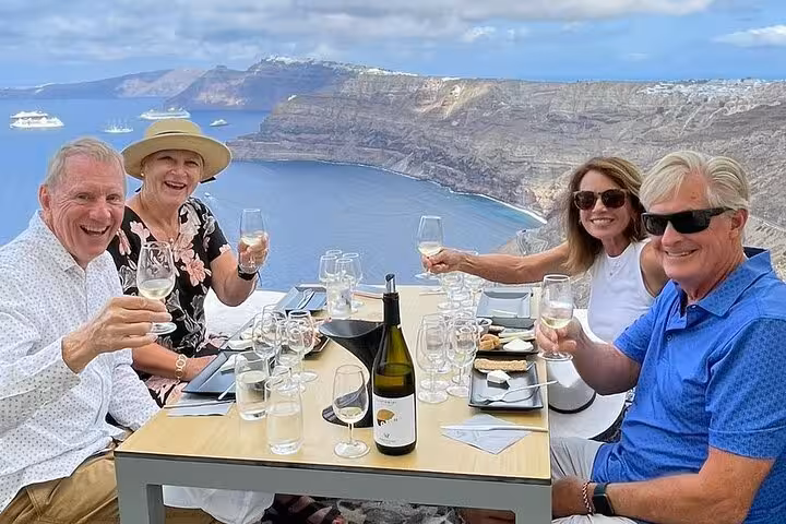 Group enjoying private Santorini wine tasting with snacks and caldera views, visiting 2 to 4 wineries and Wine Museum