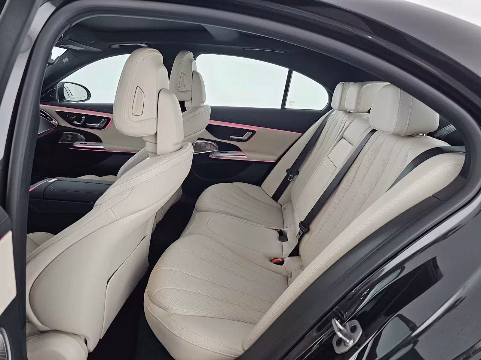 Luxury sedan rear cabin with cream leather seats and pink ambient lighting for Keflavik airport transfer