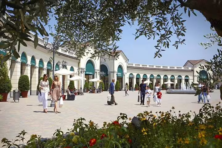 Visitors enjoy a leisurely stroll through an elegant shopping courtyard near Milan, surrounded by Mediterranean architecture.