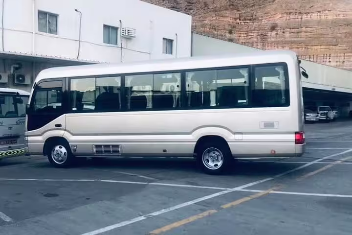 Modern beige shuttle bus parked, perfect for private transfers from Dubai to Muscat, providing reliable travel.