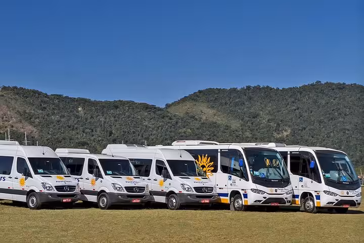 Fleet of private shuttles ready for transport from Rio de Janeiro to Buzios, surrounded by lush green hills.