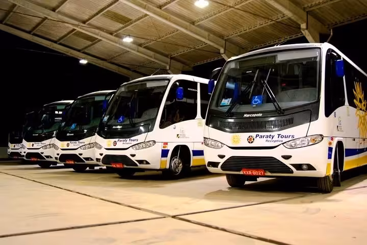 Private shuttle van from Rio de Janeiro to Buzios, operated by Paraty Tours, parked surrounded by tropical scenery.