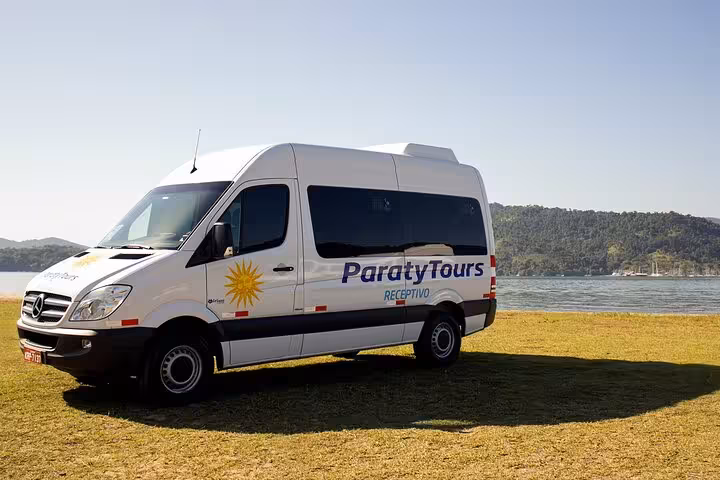 Private shuttle from Paraty Tours parked by the scenic coast, ready for transport from Rio de Janeiro to Buzios.