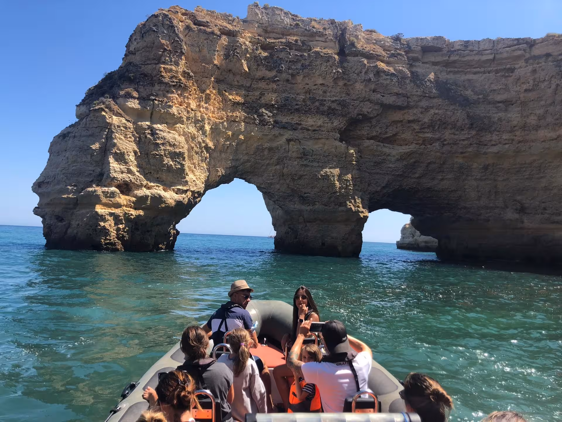 Private Algarve speedboat cave tour passing a dramatic sea arch, with small group cruising on turquoise water