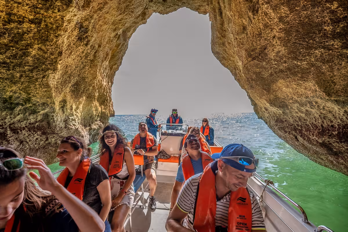 Private Algarve cave cruise with guests in life jackets on a speedboat entering a sea cave near Benagil