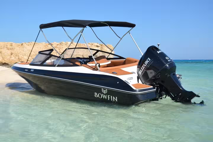 Private speedboat anchored in crystal-clear water at Magawish Island near Hurghada, Red Sea snorkeling tour