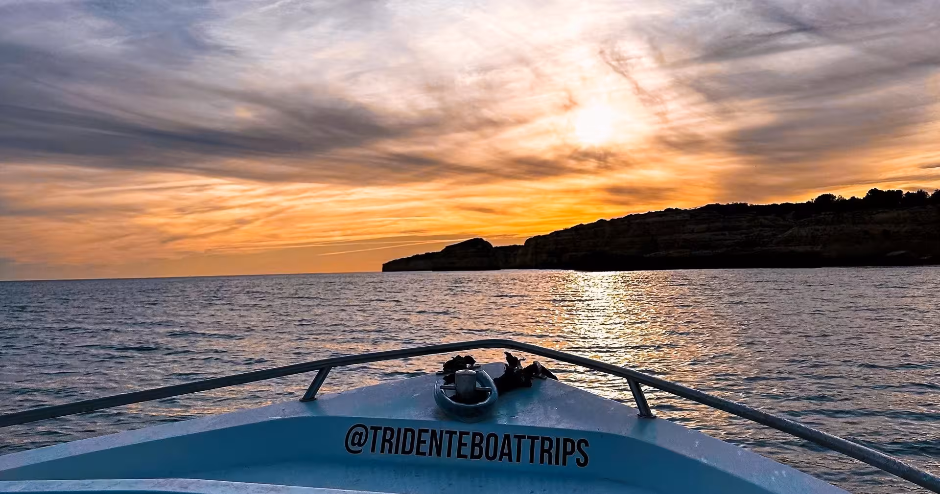Private sunset Benagil Caves boat tour in Algarve, Portugal, cruising toward dramatic cliffs under colourful evening sky