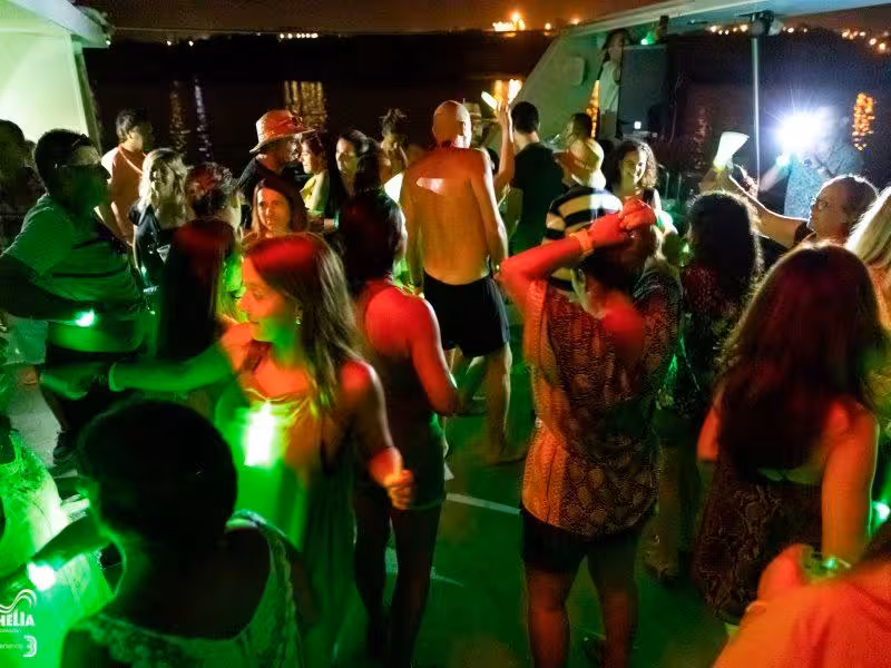 Guests dance under neon lights on a private sunset party boat, ideal for corporate events, birthdays and group celebrations