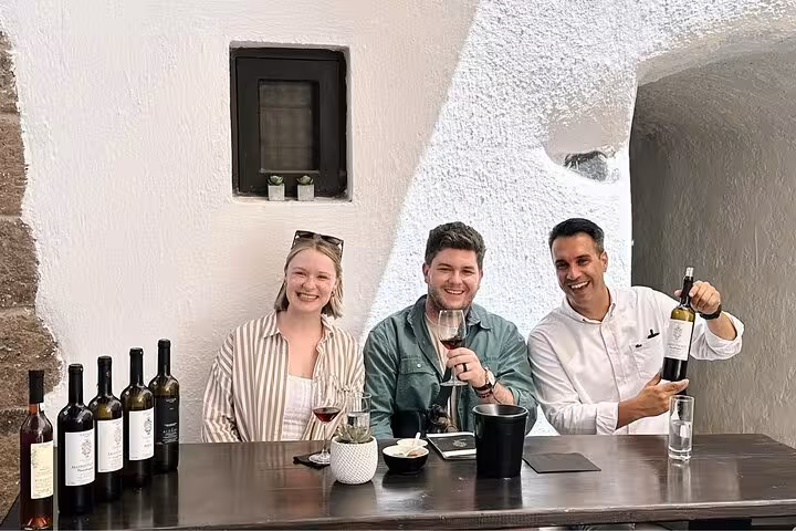Wine tasting stop on private sunset wine tour, sampling bottles at 3 wineries with tapas in Santorini