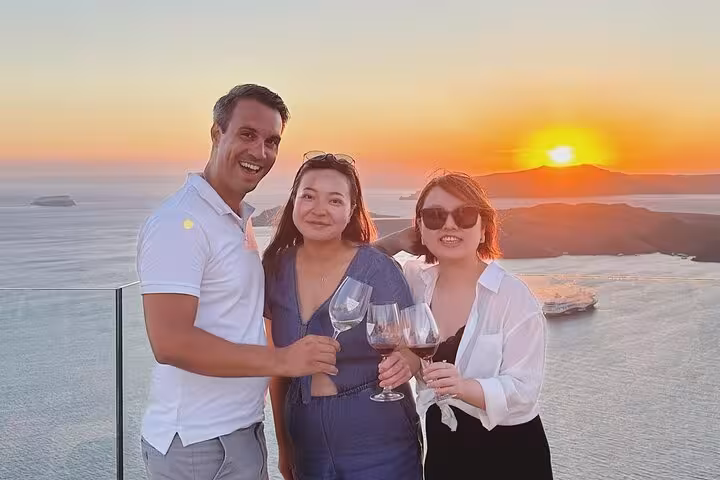 Guests toast wine at sunset viewpoint on private tour visiting 3 wineries with tapas and Aegean sea views