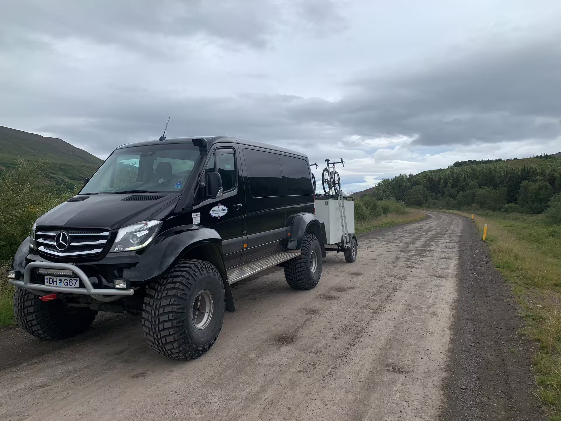 Black Mercedes Sprinter 4x4 super jeep towing trailer on Iceland gravel road