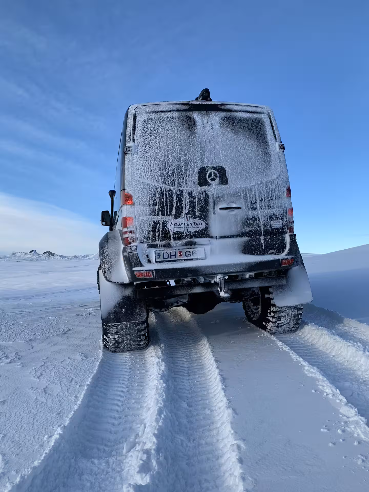 Frost-covered Mercedes Sprinter super jeep driving through snowy Iceland landscape on private guided tour