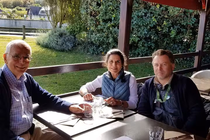 Three tourists enjoying lunch together at an outdoor restaurant terrace during a D-Day Beaches private tour from Le Havre