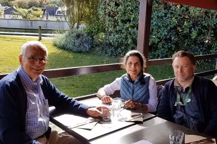 Three travelers dining at outdoor restaurant terrace near Mont Saint-Michel during private tour from Cherbourg